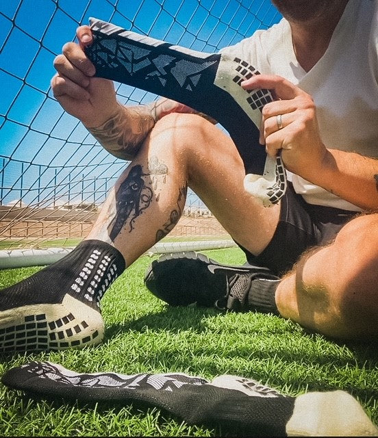 photo of man showing black grip socks in the sun